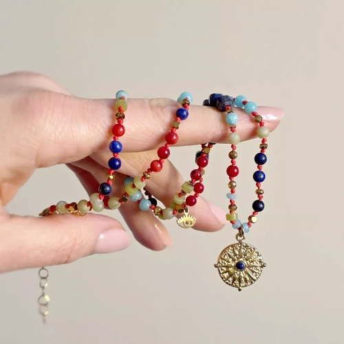 Unikatowy naszyjnik supełkowany z lapis lazuli, koralu, amazonitu, jadeitu i hematytu na czerwonym sznurku z zawieszką słońce i oko – biżuteria z naturalnych kamieni. Magneska.pl