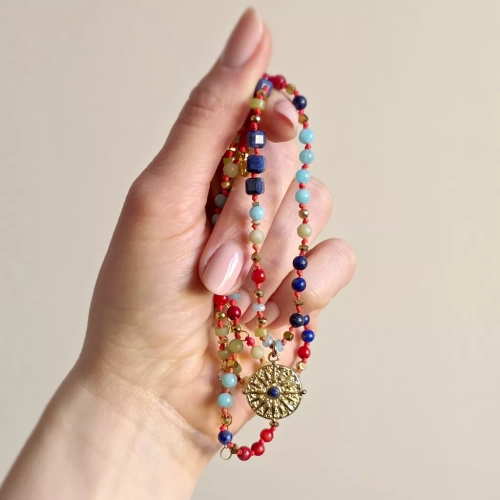 Unikatowy naszyjnik supełkowany z lapis lazuli, koralu, amazonitu, jadeitu i hematytu na czerwonym sznurku z zawieszką słońce i oko – biżuteria z naturalnych kamieni. Magneska.pl