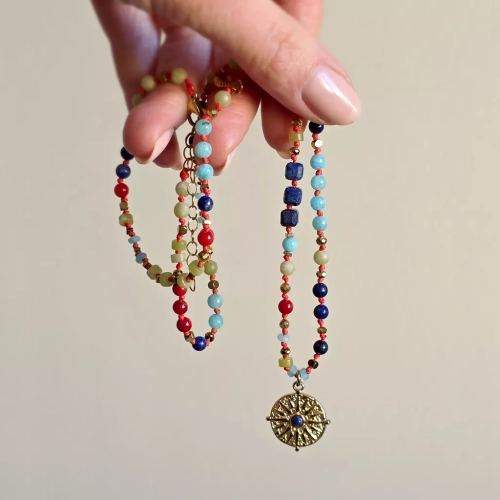 Unikatowy naszyjnik supełkowany z lapis lazuli, koralu, amazonitu, jadeitu i hematytu na czerwonym sznurku z zawieszką słońce i oko – biżuteria z naturalnych kamieni. Magneska.pl