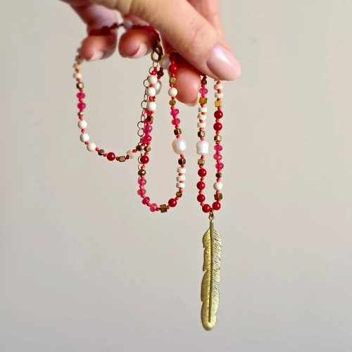 Unikatowy naszyjnik supełkowany z agatu, koralu, perły, kamienia rzecznego i hematytu na czerwonym sznurku z zawieszką pióro – biżuteria z naturalnych kamieni. Magneska.pl