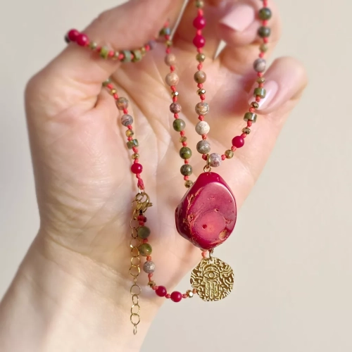 Unikatowy naszyjnik supełkowany z koralu, unakitu, jaspisu leopardziego i złotego hematytu na czerwonym sznurku z medalionem hamsa zawieszonym pod dużym plastrem korala – biżuteria z naturalnych kamieni Magneska.pl