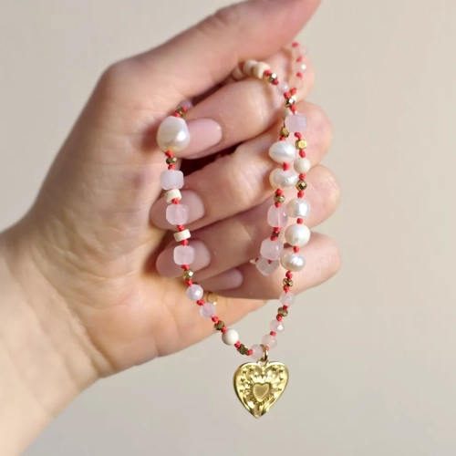Unikatowy naszyjnik supełkowany z kwarcu różowego, agatu, perły, kamienia rzecznego i złotego hematytu na czerwonym sznurku z zawieszką serce z tłoczeniem dłoni unoszących promieniste serce – biżuteria Magneska.pl.