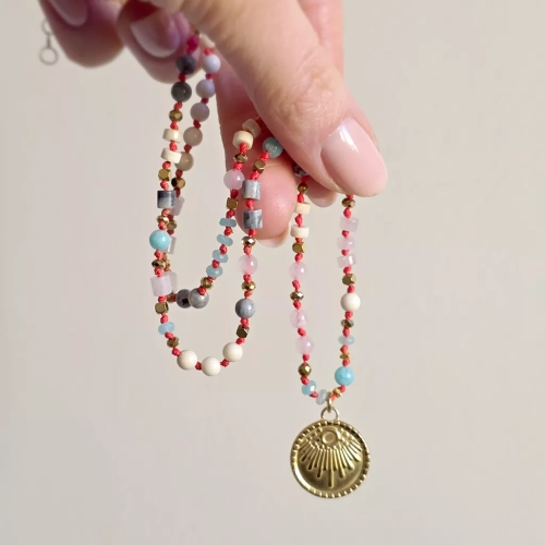 Unikatowy naszyjnik supełkowany z kwarcu różowego, amazonitu, kamienia rzecznego, jaspisu szarego i złotego hematytu na czerwonym sznurku z medalionem słońce – biżuteria z naturalnych kamieni Magneska.pl