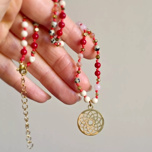 Unikatowy naszyjnik supełkowany z jaspisu dalmatyńskiego, koralu, kwarcu różowego, kamienia rzecznego i złotego hematytu na czerwonym sznurku z ażurową mandalą, zawieszką z czerwonym oczkiem i blaszką Magneska – biżuteria z naturalnych kamieni Magneska.pl